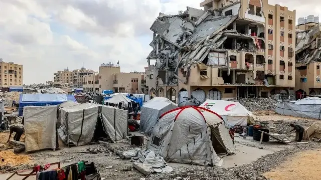 Des tentes abritant des Palestiniens déplacés par le conflit à Gaza City sont installées près de bâtiments endommagés dans le complexe résidentiel Hamad City, construit par le Qatar, au nord-ouest de Khan Yunis, dans le sud de la bande de Gaza, le 22 septembre 2025. 