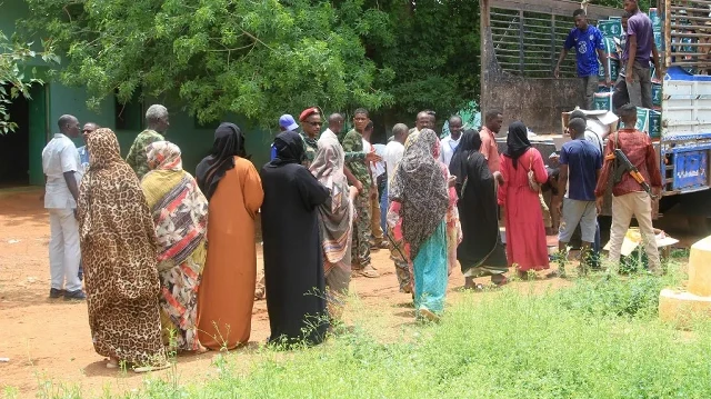 Des Soudanais récemment revenus après avoir été déplacés font la queue pour recevoir de l'aide humanitaire à Ombada, à l'ouest d'Omdurman, le 24 août 2025.