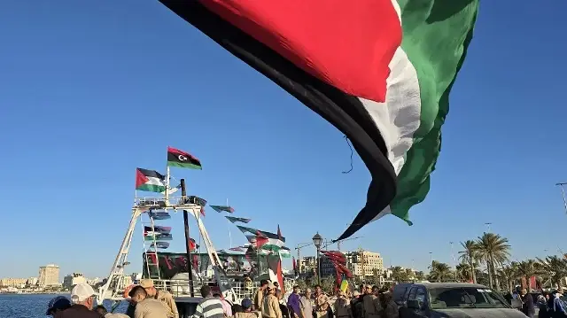 Des personnes posent devant le navire Omar al-Mukhtar, un bateau libyen parti en mer le 17 septembre pour rejoindre la Flottille mondiale Sumud, au port de Tripoli le 16 septembre 2025.