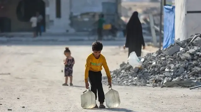 Un garçon palestinien déplacé par le conflit transporte des bidons d’eau dans le complexe résidentiel Hamad City, construit par le Qatar, au nord-ouest de Khan Younis, dans le sud de la bande de Gaza, le 24 septembre 2025.
