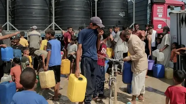 Des Palestiniens déplacés tentent de remplir des conteneurs d'eau dans la région de Mawasi, à Khan Yunis, le 14 août 2025, alors que les organisations internationales s'efforcent de fournir de l'eau potable à la population dans un contexte de crise qui s'aggrave et de propagation de maladies dues au manque d'hygiène dans la bande de Gaza.