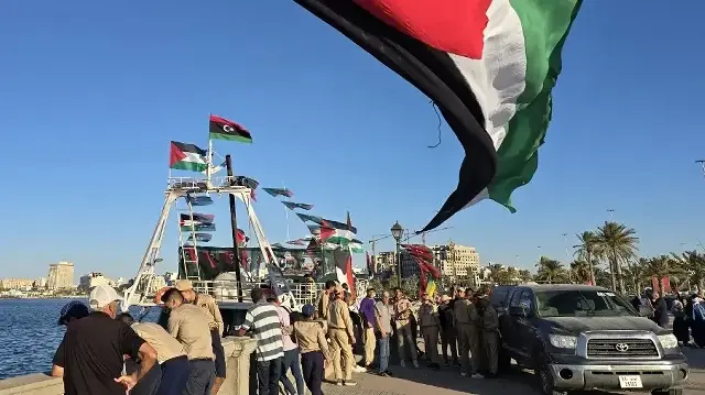 Des personnes posent pour une photo devant le navire Omar al-Mukhtar, un navire libyen qui a pris la mer le 17 septembre pour rejoindre la flottille mondiale Sumud, dans le port de Tripoli, le 16 septembre 2025.