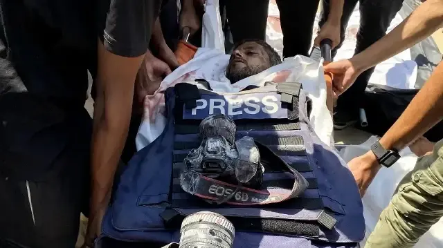 Des personnes en deuil transportent le corps du photojournaliste palestinien Hussam al-Masri, un collaborateur de Reuters tué lors d'une frappe israélienne sur l'hôpital Nasser à Khan Yunis, dans le sud de la bande de Gaza, lors de ses funérailles le 25 août 2025.  