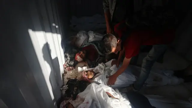 Des Palestiniens identifient les corps des personnes tuées lors des bombardements israéliens, à l'intérieur d'une structure préfabriquée devant l'hôpital al-Awda dans le camp de réfugiés de Nuseirat, dans le centre de la bande de Gaza, le 28 septembre 2025. 