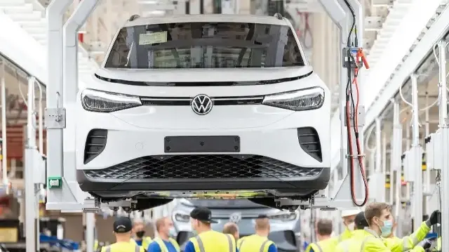 Des employés travaillent sur la chaîne de montage d'une voiture électrique ID.4 de Volkswagen (VW) lors du lancement de sa production sur le site du constructeur automobile allemand Volkswagen à Emden, dans le nord de l'Allemagne, le 20 mai 2022.