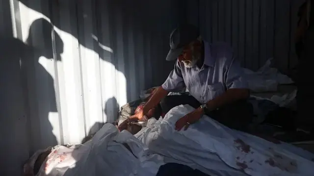 Un Palestinien fait ses adieux à un homme tué lors d’un bombardement israélien, dans une structure préfabriquée installée devant l’hôpital al-Awda, dans le camp de réfugiés de Nuseirat, au centre de la bande de Gaza, le 28 septembre 2025.