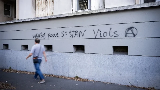 Un homme passe devant un graffiti intitulé "Vérité pour les viols de Saint Stan (pour Stanislas)" dans une rue proche de l'entrée du lycée et collège privé catholique Saint-Stanislas à Nantes, dans l'ouest de la France, le 29 août 2025.