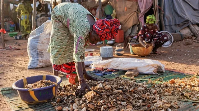 Une femme trie les déchets alimentaires à l'extérieur d'un abri de fortune dans le camp de déplacés de Faladie, à Bamako, le 9 novembre 2022. Les personnes fuyant le conflit qui sévit au Mali depuis une décennie se réfugient dans le camp de déplacés de Faladie.