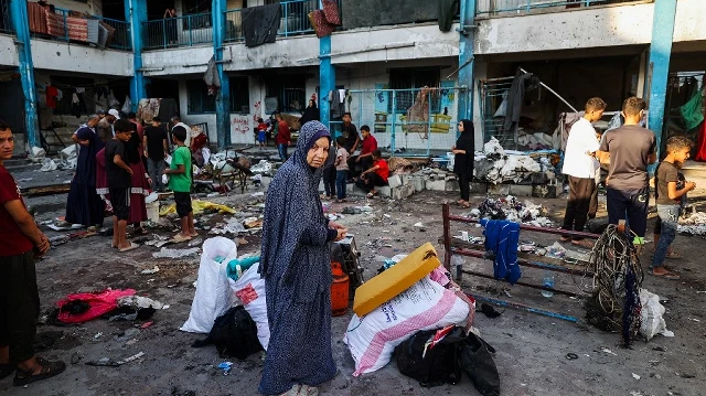 Des Palestiniens récupèrent des objets dans les décombres d'une tente touchée par des frappes israéliennes la veille, à l'école pour filles Abou Helou gérée par l'UNRWA dans le camp de réfugiés de Bureij, dans le centre de la bande de Gaza, le 17 juillet 2025.