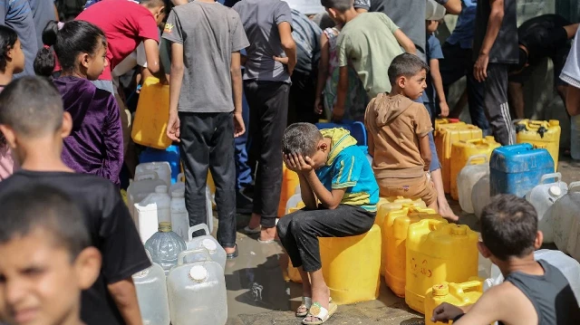 Des enfants palestiniens assis sur leurs bidons font la queue pour obtenir de l'eau dans un centre de distribution caritatif du camp de réfugiés de Nuseirat, dans la bande de Gaza assiégée par Israël, le 4 septembre 2025, où l'ONU a déclaré une famine après près de deux ans de guerre.
