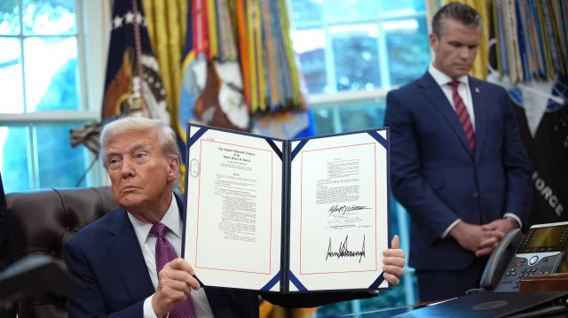 Le président américain Donald Trump brandit la loi sur la protection de la vie privée des acheteurs immobiliers après l'avoir signée en présence du secrétaire à la Défense Pete Hegseth, lors d'une conférence de presse dans le bureau ovale de la Maison Blanche, le 5 septembre 2025 à Washington, DC. Le président Trump a signé une série de décrets, dont celui renommageant le ministère de la Défense en ministère de la Guerre.