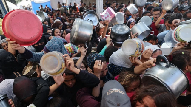 Des Palestiniens se bousculent pour recevoir un repas chaud distribué par une cuisine caritative dans le camp de réfugiés de Nuseirat, dans la bande de Gaza assiégée par Israël, le 4 septembre 2025, où l'ONU a déclaré une famine après près de deux ans de guerre.