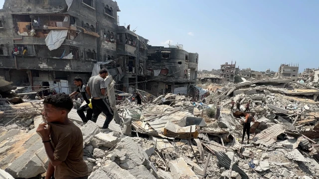 Des Palestiniens marchent parmi les décombres d'un bâtiment détruit à Jabalia, dans le nord de la bande de Gaza, le 9 août 2025.
