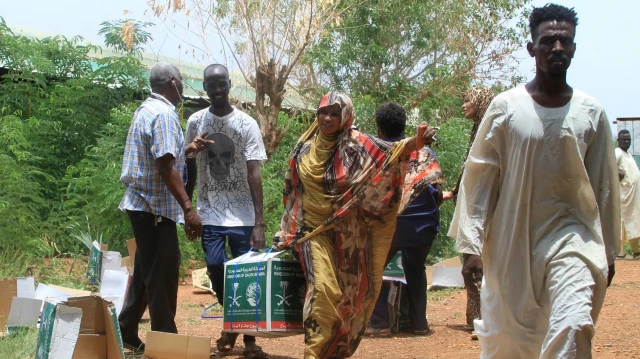 Des Soudanais récemment revenus après avoir été déplacés font la queue pour recevoir de l'aide humanitaire à Ombada, à l'ouest d'Omdurman, le 24 août 2025.
