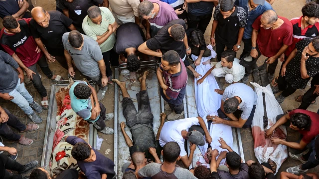 Des personnes entourent les cadavres de Palestiniens, certains tués tôt le matin lors de frappes israéliennes et d'autres tués la veille alors qu'ils cherchaient de l'aide humanitaire près de Zikim, à l'ouest de Beit Lahia, dans la cour de l'hôpital al-Shifa à Gaza, le 7 septembre 2025.