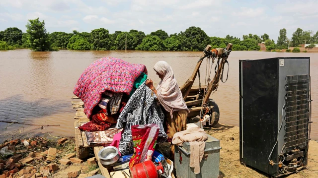 سیلاب متاثرہ علاقے میں ایک خاندان اپنا بچا کچھا سامان لے کر پناہ کا منتظر ہے۔