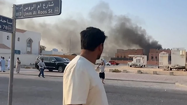 Cette image tirée d'une vidéo AFPTV montre un homme regardant la fumée qui s'élève après des explosions à Doha, capitale du Qatar, le 9 septembre 2025.