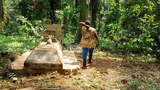 Judith Kahindo, 40 ans, originaire de la province d'Ituri et déplacée par les massacres perpétrés par le groupe armé Forces démocratiques alliées (ADF) en 2021, marche près de la tombe de son père dans son champ à Mavivi, dans la banlieue de Beni, au Nord-Kivu, dans l'est de la République démocratique du Congo, le 14 décembre 2024. 