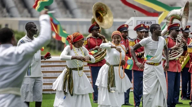 Des artistes agitent des drapeaux éthiopiens et dansent sur des chants traditionnels lors de la cérémonie officielle d'inauguration du Grand barrage de la Renaissance éthiopienne (GERD) à Guba, le 9 septembre 2025. 