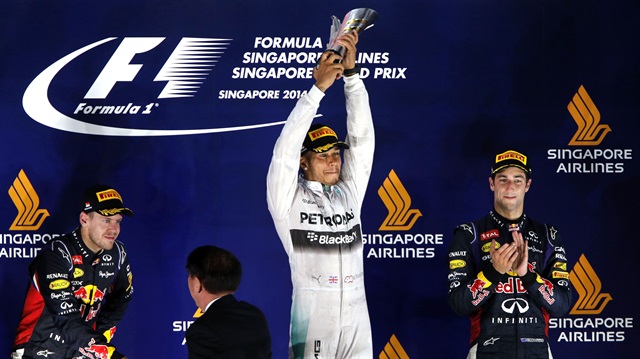 Mercedes F1 driver Lewis Hamilton (C) of Britain raises his trophy during the podium ceremony after winning the Singapore F1 Grand Prix 