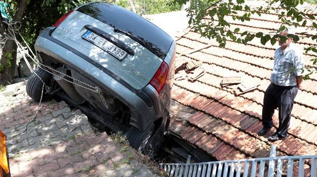 İstanbul Ümraniye'de sürücüsünün el frenini çekmeden park ettiği aracı, bir evin çatısına düştü.