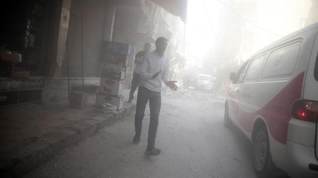 Men walk amidst dust after shelling in the rebel held besieged town of Douma, 