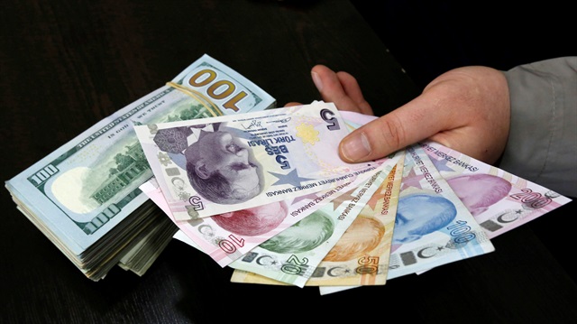 A money changer holds Turkish lira banknotes next to U.S. dollar bills at a currency exchange office in central Istanbul