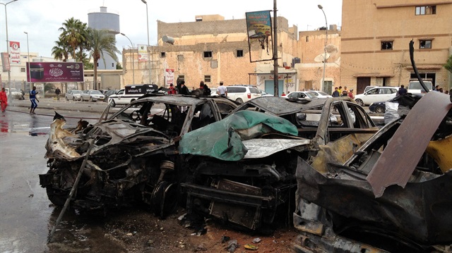 People look at the remnants of a car at the scene of a car bomb in Benghazi, Libya