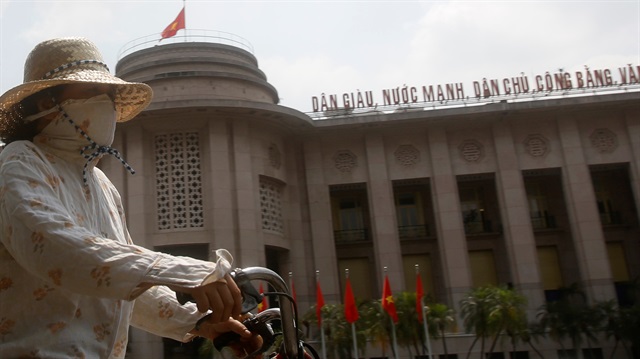 A woman rides a bicycle past the building of the State Bank of Vietnam in Hanoi