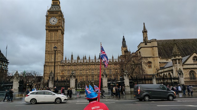A man waves a British flag near the Big Ben in London, UK