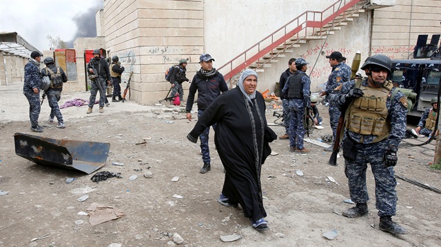 A displaced Iraqi woman flees from clashes during a battle between Iraqi forces and Daesh in Mosul