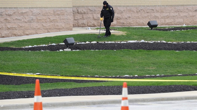 An Overland Park Police officer uses a metal detector as he searches for evidence at the scene of Sunday's fatal shooting at the Jewish Community Center of Greater Kansas City in Overland Park, Kansas 
