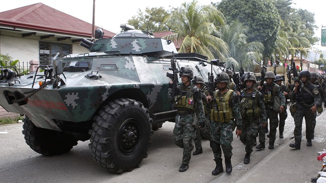 Members of the elite Special Action Police walk next to an armoured vehicle