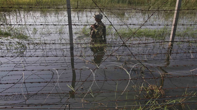 An Indian Border Security Force (BSF) soldier patrols the fenced border with Pakistan 