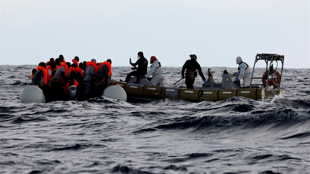 Italian Navy personnel rescue migrants from their overcrowded raft