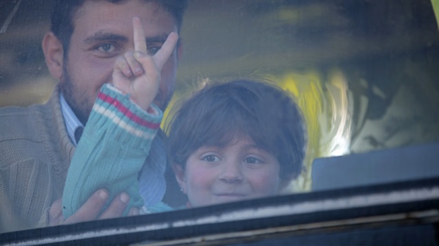 A man holding a boy inside a bus carrying opposition fighters and their families who evacuated the Waer neighborhood in Homs