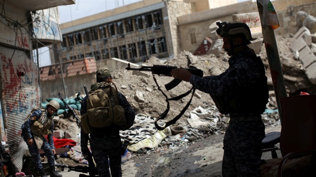 A member of the Iraqi Federal Police takes his rifle to hang it on his shoulder