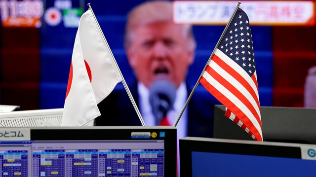 National flags of Japan and the U.S. are seen in front of a monitor showing U.S. President Donald Trump at a foreign exchange trading company in Tokyo.