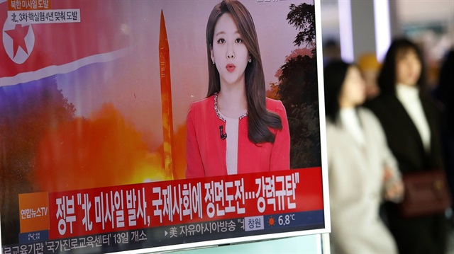 Women walk past a TV screen broadcasting a news report on North Korea firing a ballistic missile
