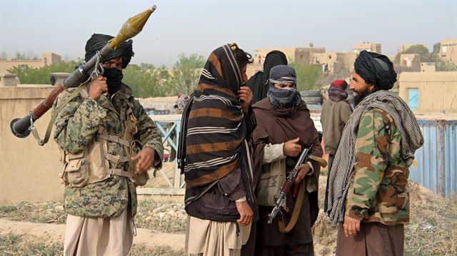 Members of the Taliban gather at the site of the execution of three men