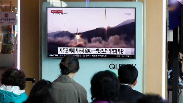 People watch a TV broadcasting of a news report on North Korea's missile launch