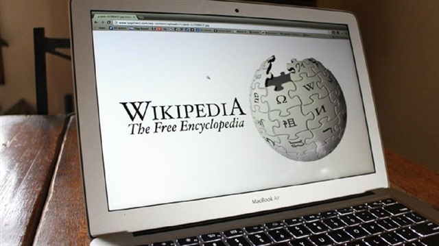 A laptop screen shows the logo of Wikipedia