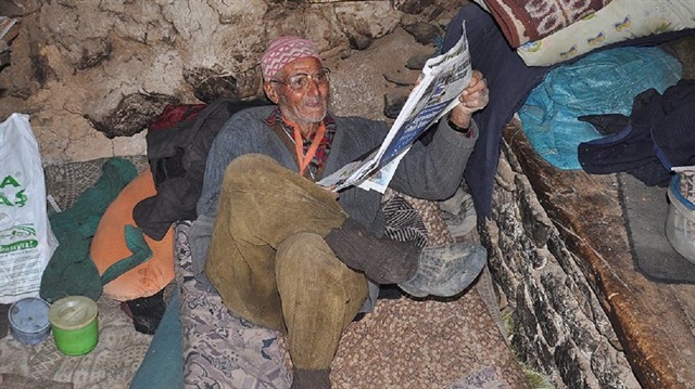 81 yaşındaki keçi çobanı Durali Kaba, gündemi eski gazetelerden takip ediyor.