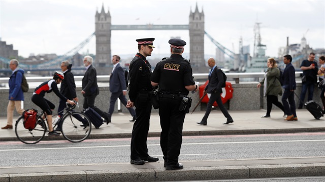 Commuters travel past City of London police officers standing on London Bridge after is was reopened following an attack which left 7 people dead and dozens of injured in central London, Britain, June 5, 2017.