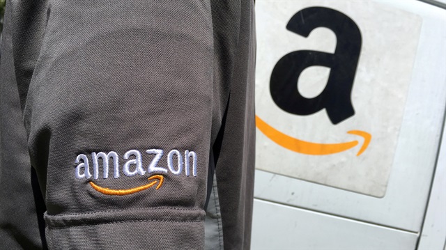 FILE PHOTO - An Amazon.com Inc driver stands next to an Amazon delivery truck 