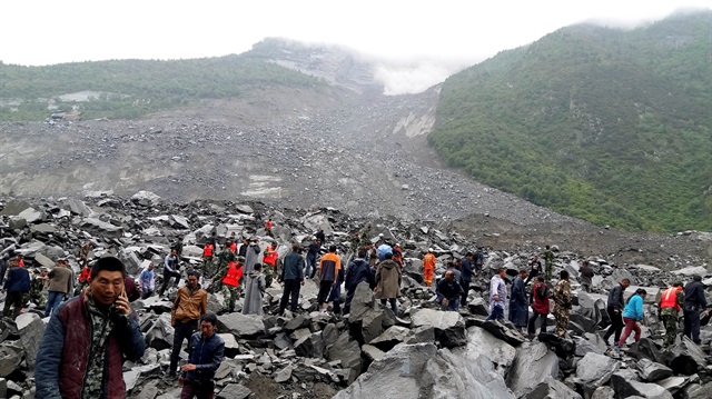 People search for survivors at the site of a landslide that destroyed some 40 households, where more than 100 people are feared to be buried, local media reports, in Xinmo Village, Sichuan Province, China June 24, 2017.