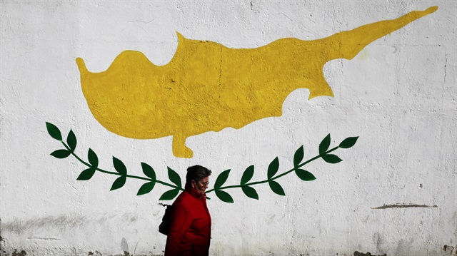 A woman walks in front of Cypriot flag painted on a wall in capital Nicosia, Cyprus