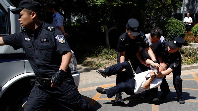 Police detain a man as people protest against a local authoritiy's decision to reassign their children to an undesired school in Beijing, China June 14, 2017.