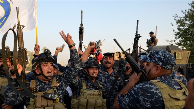 Iraqi security forces celebrate as Prime Minister Haider al-Abadi announces victory over Daesh.