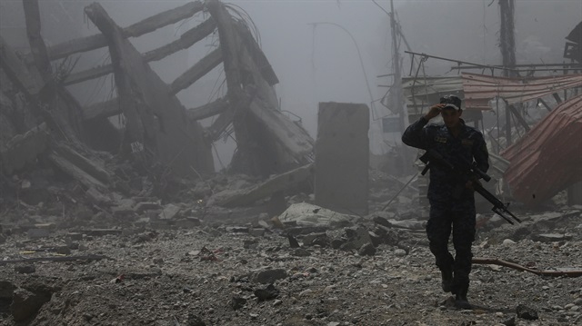 A member of Iraqi Federal police walks along destroyed buildings from clashes in the Old City of Mosul, Iraq